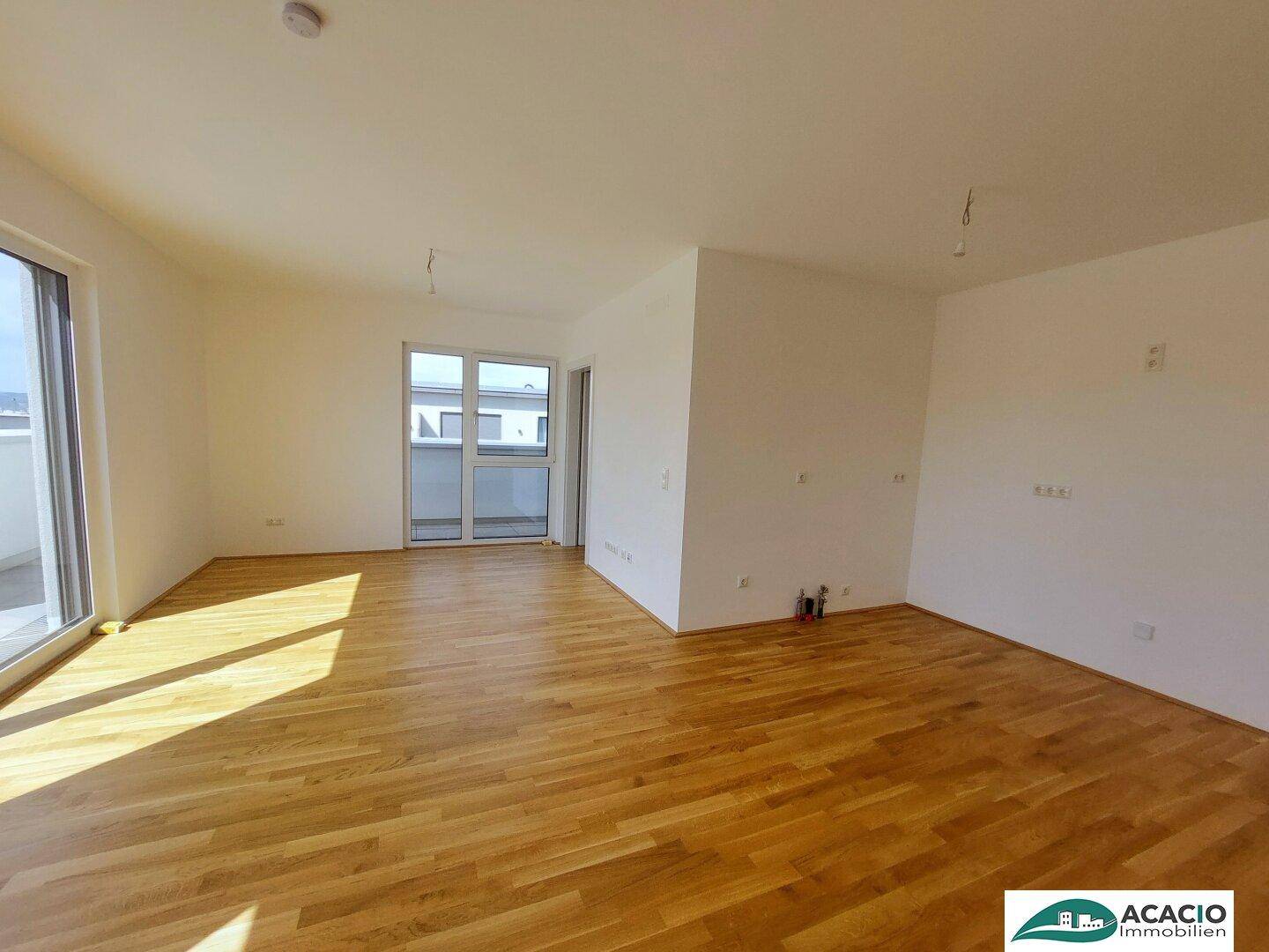 Lichtdurchfluteter Wohnbereich mit Parkettboden und Zugang zu einem weiteren Balkon.