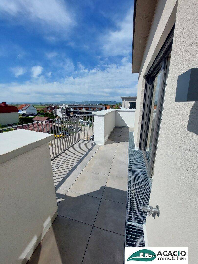 Heller Balkon mit Fliesenboden und Metallgeländer, bietet einen weiten Ausblick.