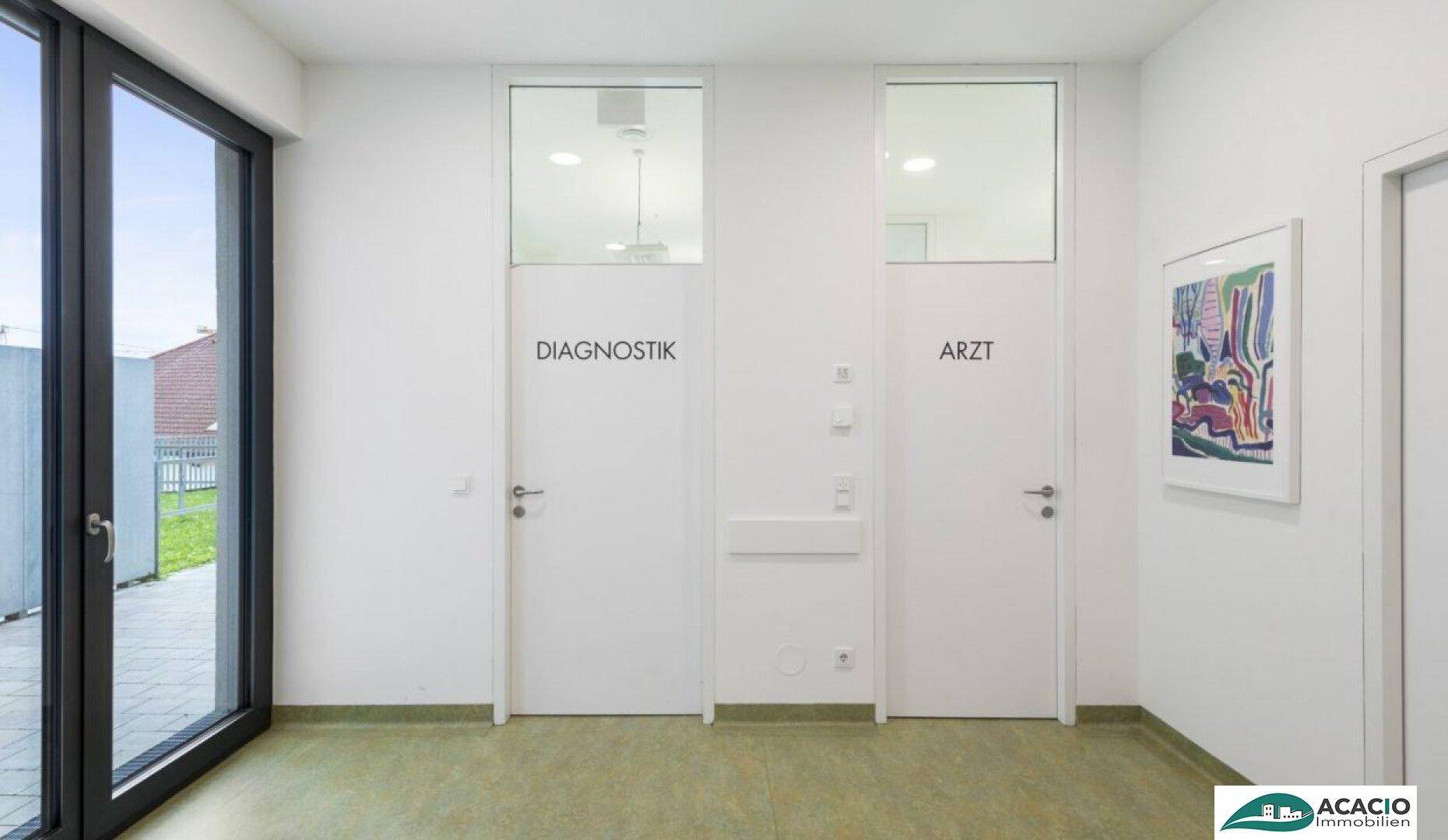 Heller Flur in einer Arztpraxis mit Türen zu Diagnostik- und Arztzimmern sowie einem großen Fenster.