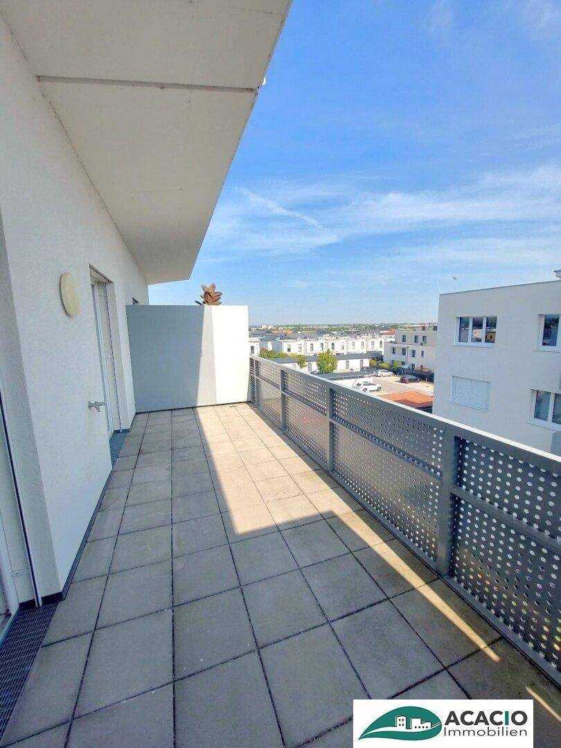 Geräumiger Balkon mit Fliesenboden und Blick auf die umliegenden Gebäude.