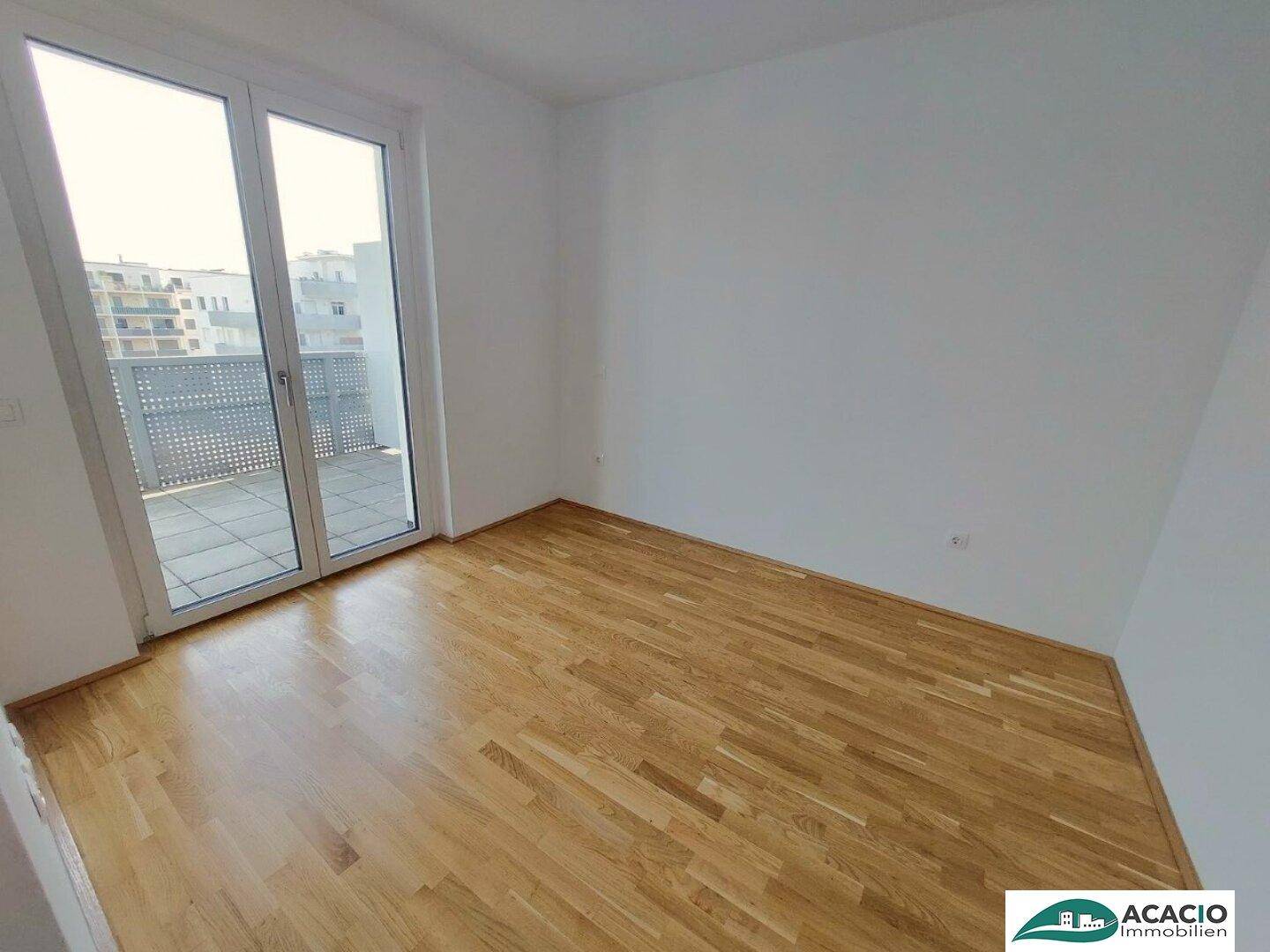 Helles Schlafzimmer mit Holzboden und direktem Zugang zu einem Balkon.