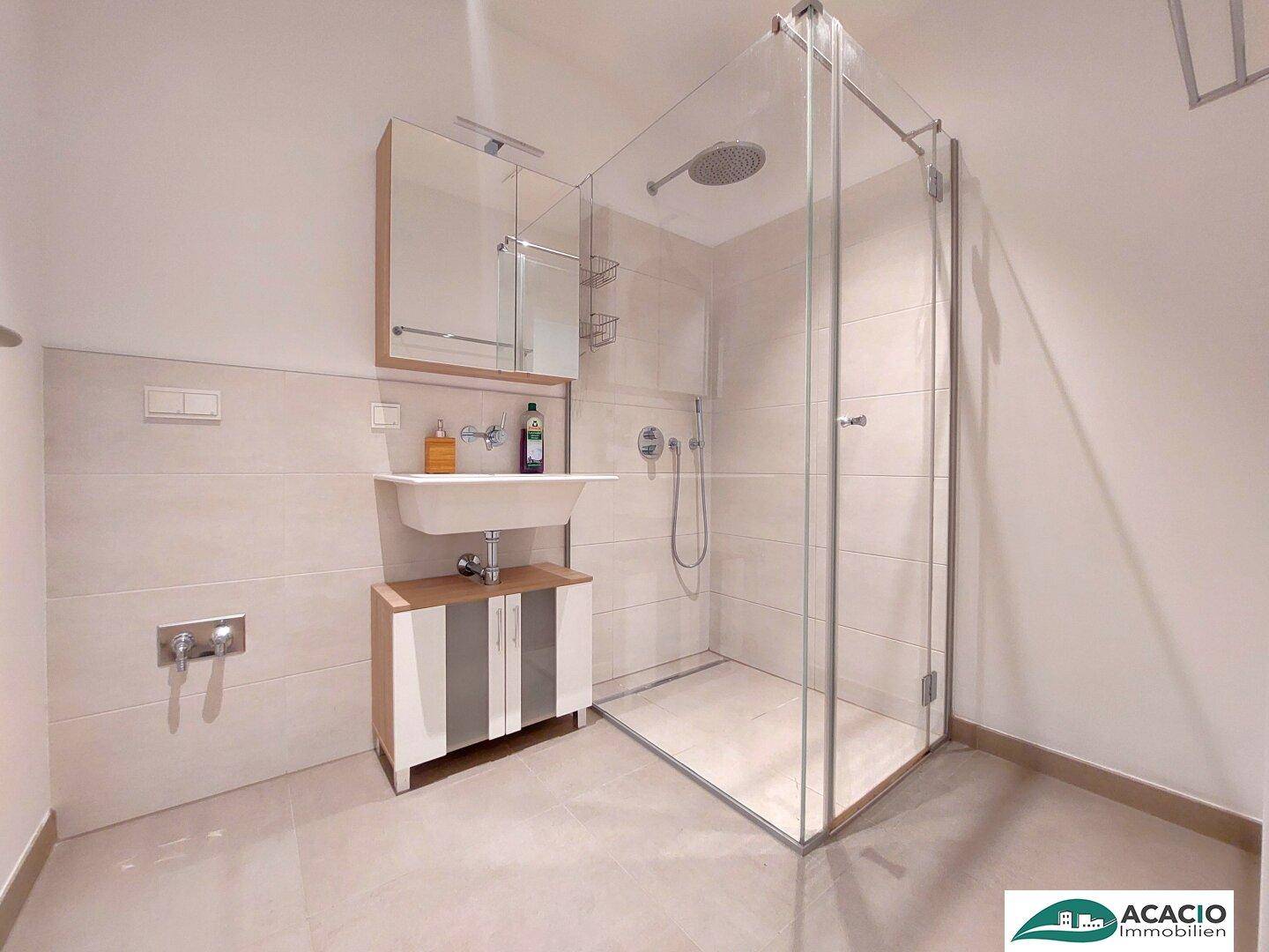 Modernes Badezimmer mit begehbarer Dusche, hellen Fliesen und einem einzelnen Waschbecken.