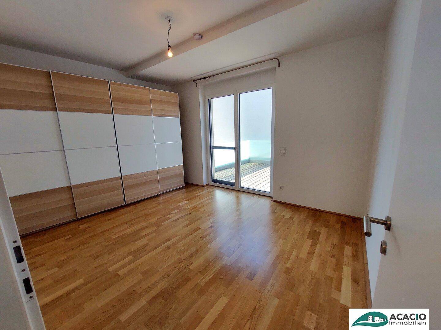 Helles Schlafzimmer mit Holzboden, großem Kleiderschrank und Zugang zu einer Terrasse.