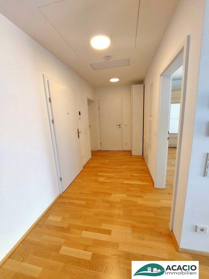 Heller Flur mit Holzboden und mehreren Türen, der zu den verschiedenen Zimmern führt.