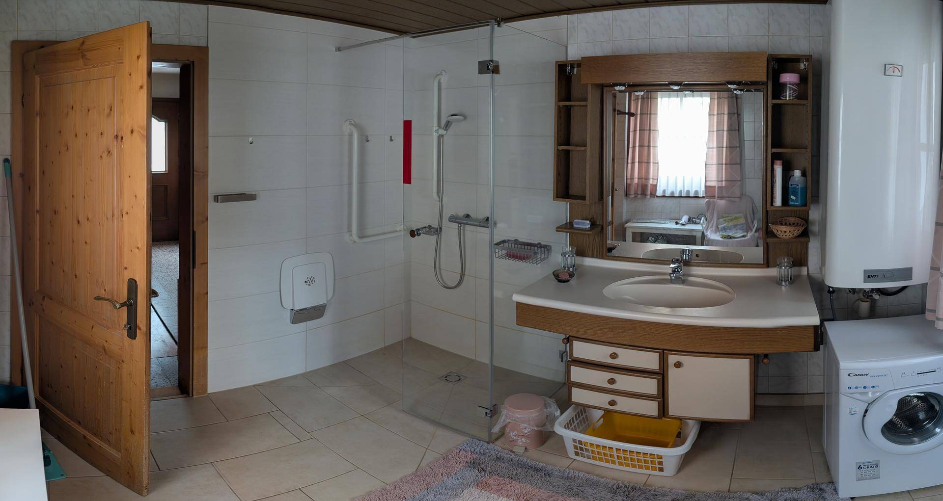 Geräumiges Badezimmer mit ebenerdiger Dusche, Einzelwaschbecken und Waschmaschine.