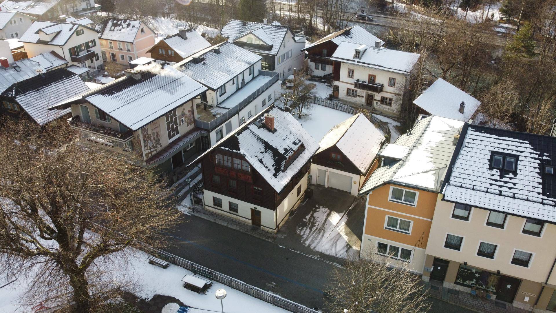 Luftaufnahme einer verschneiten Wohnsiedlung mit mehreren Häusern und Dächern.