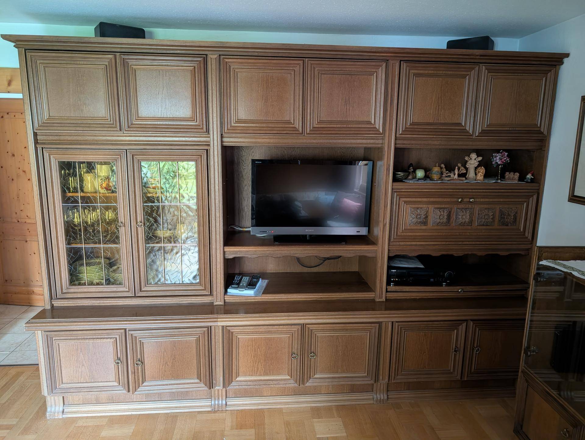 Traditionelle Holzschrankwand mit integriertem Fernseher und viel Stauraum im Wohnbereich.