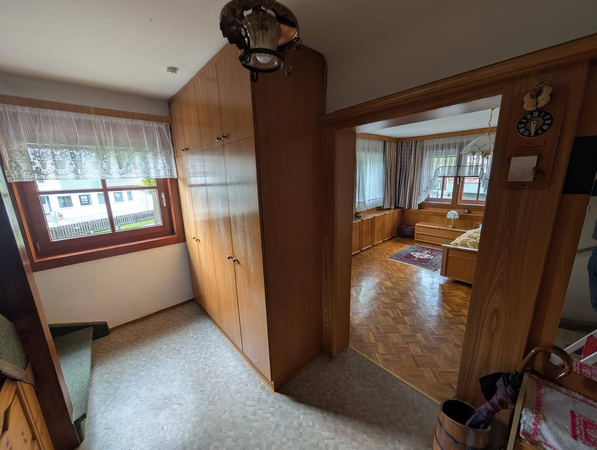 Flur mit Einbauschränken, Holzboden und Fenster, führt zu einem Schlafzimmer.
