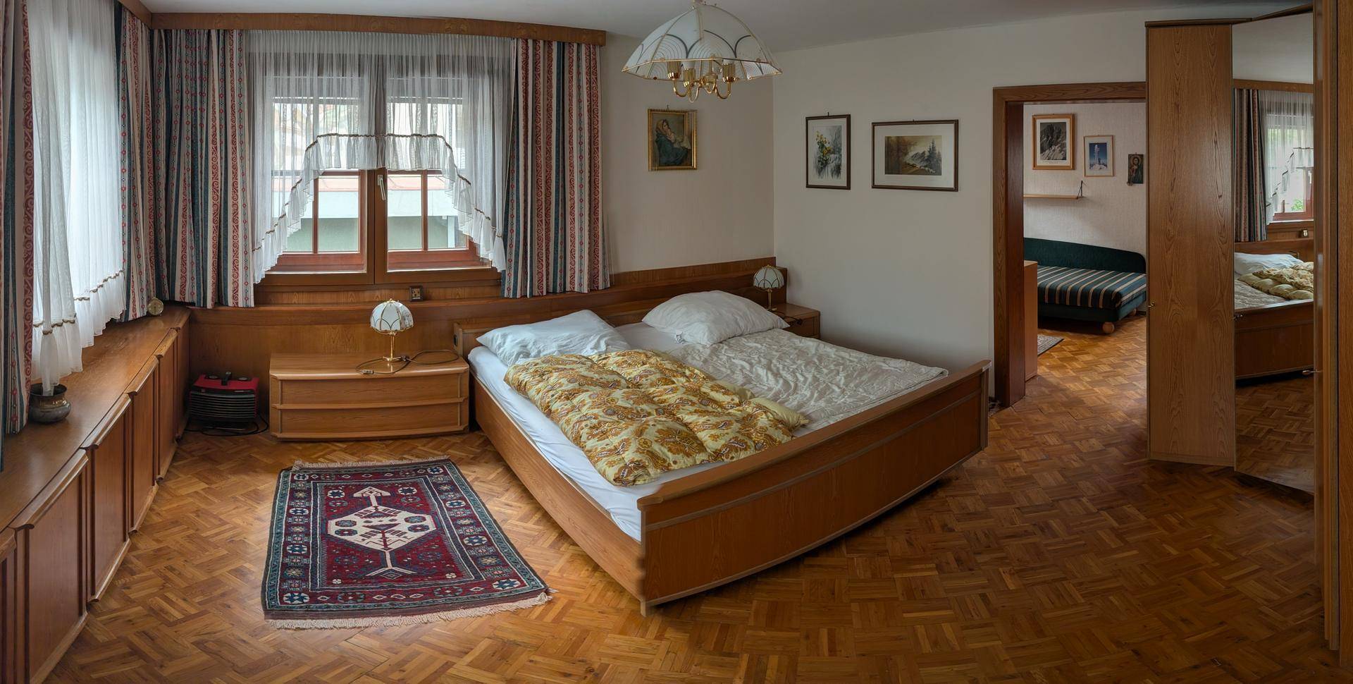 Geräumiges Schlafzimmer mit Doppelbett, Holzboden und traditionellen Holzmöbeln.