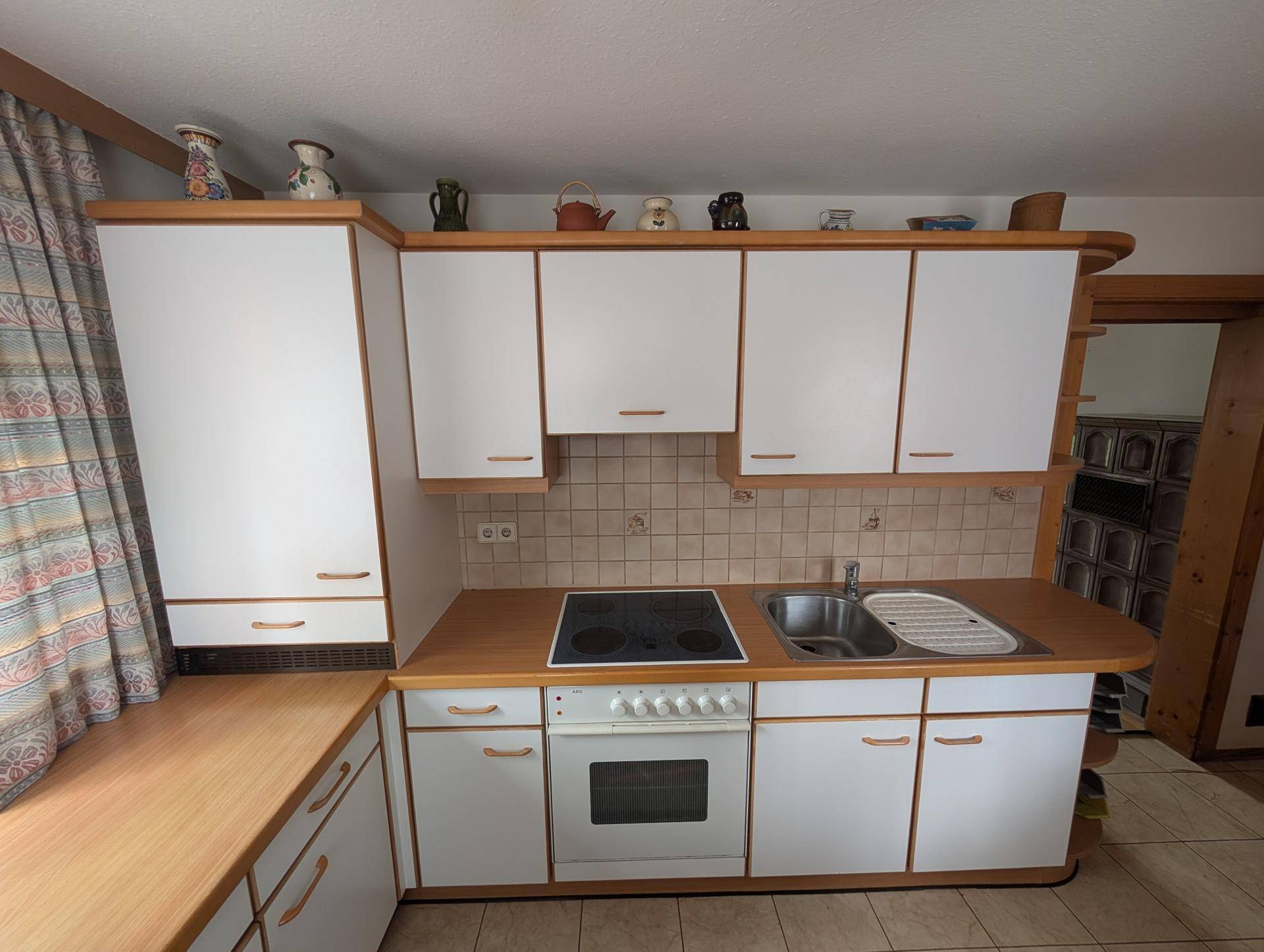 Funktionale Küche mit weißen Schränken, Holztheke und integriertem Kochfeld und Ofen.