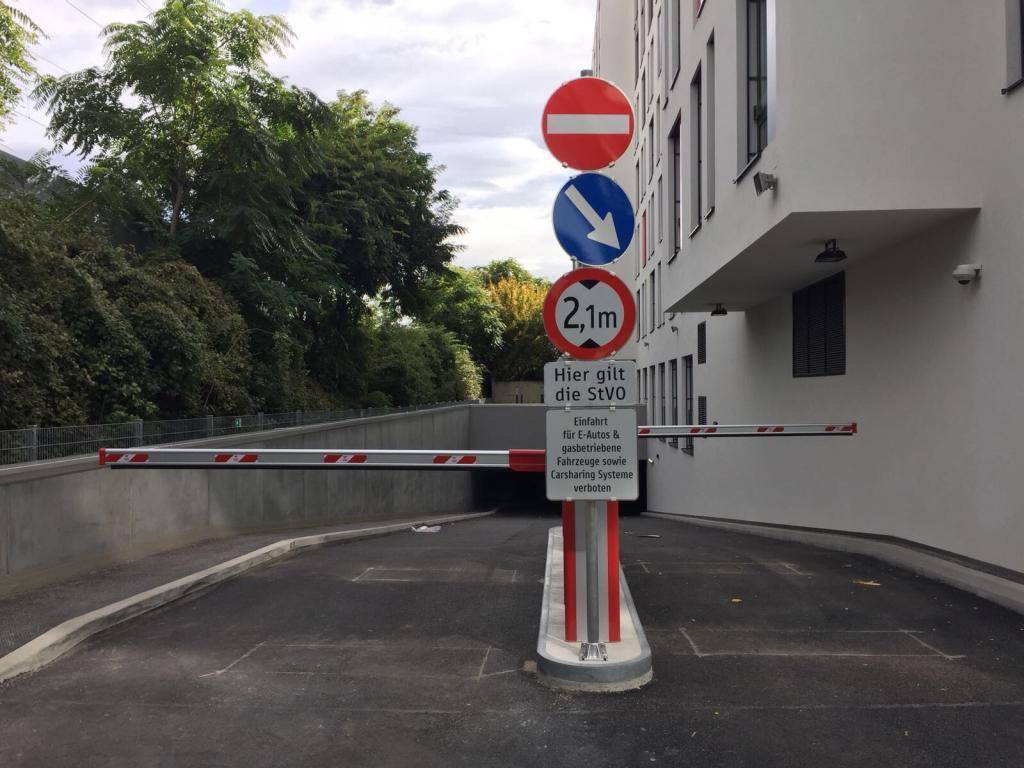Einfahrt zur Tiefgarage mit Schranke, Verkehrsschildern und Höhenbegrenzung von 2,1 Metern.