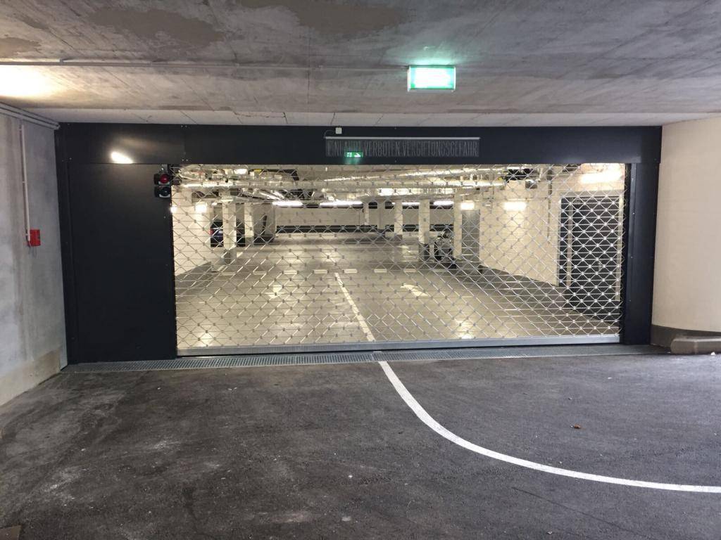 Eingang zur Tiefgarage mit geschlossenem Rolltor und Blick auf weitere Parkplätze.
