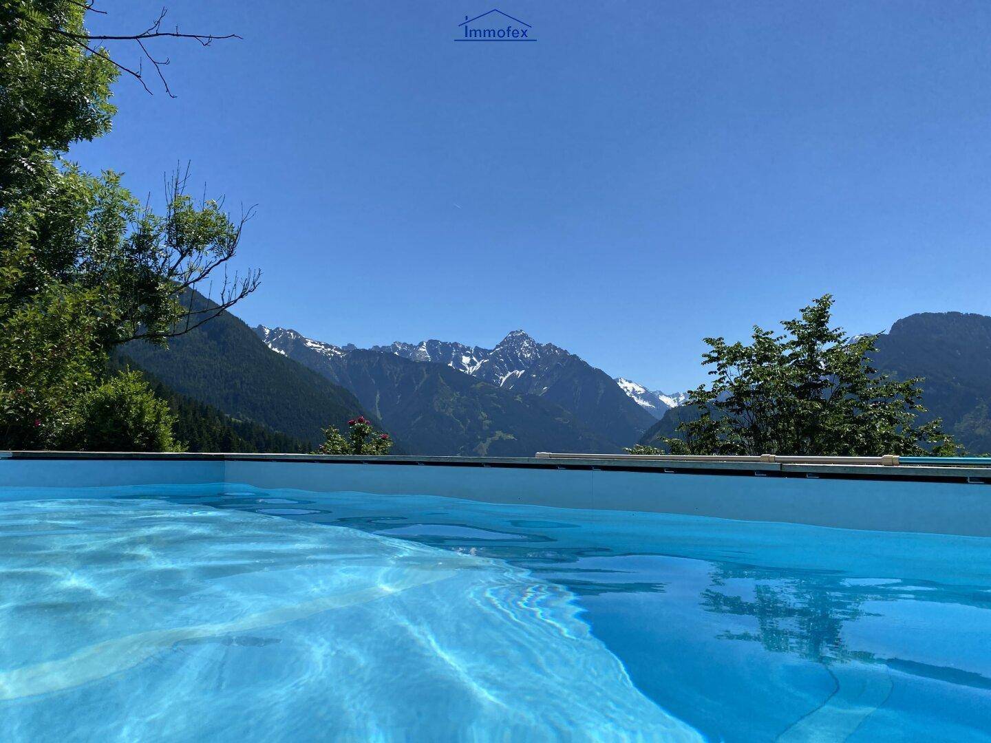 Außenpool mit klarem Wasser und einem beeindruckenden Panoramablick auf die schneebedeckten Berge.