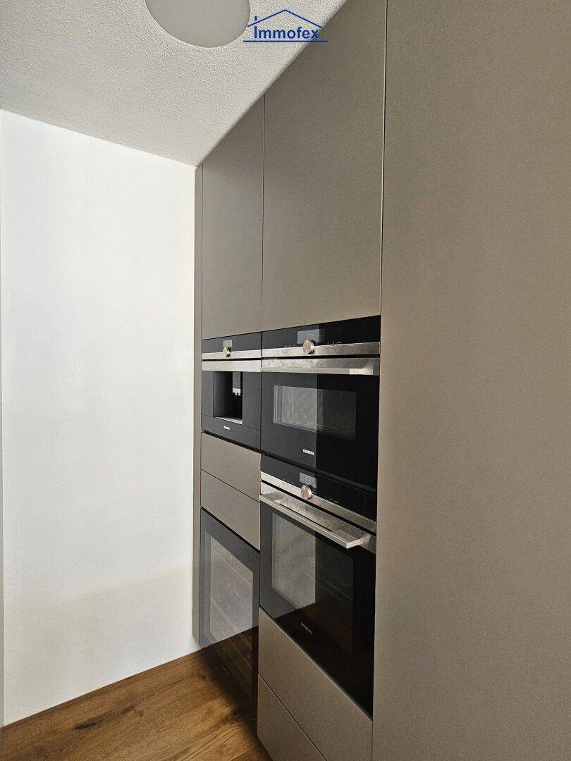 Hochwertige Einbaugeräte in der Küche, darunter Backofen, Mikrowelle und Kaffeemaschine.