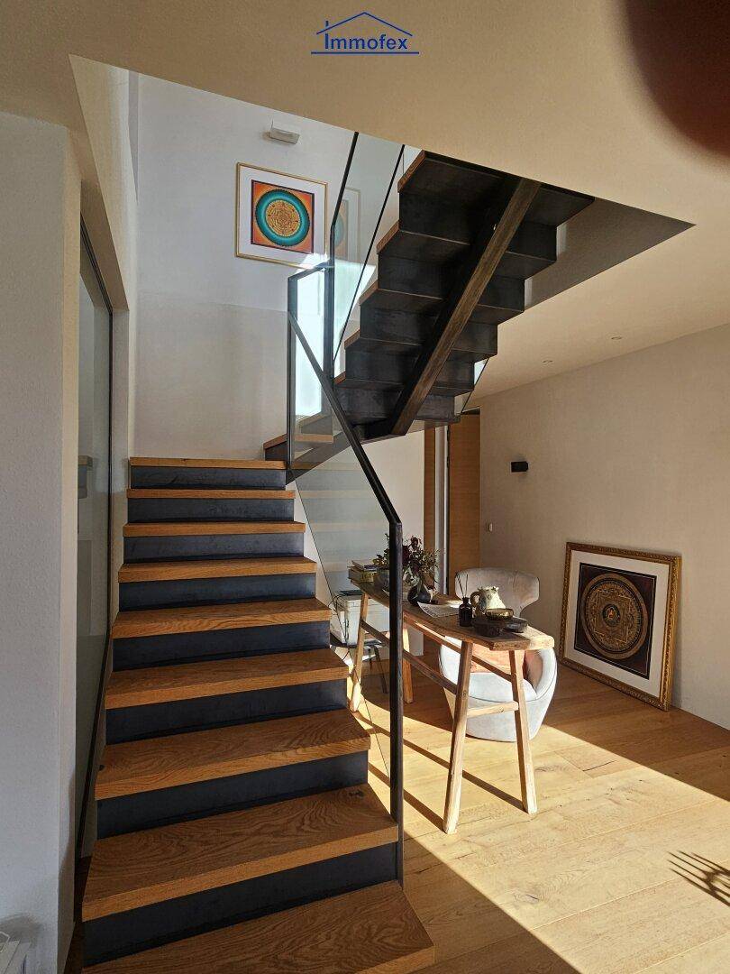 Moderne Holztreppe mit Glasgeländer, die verschiedene Ebenen des Hauses verbindet.
