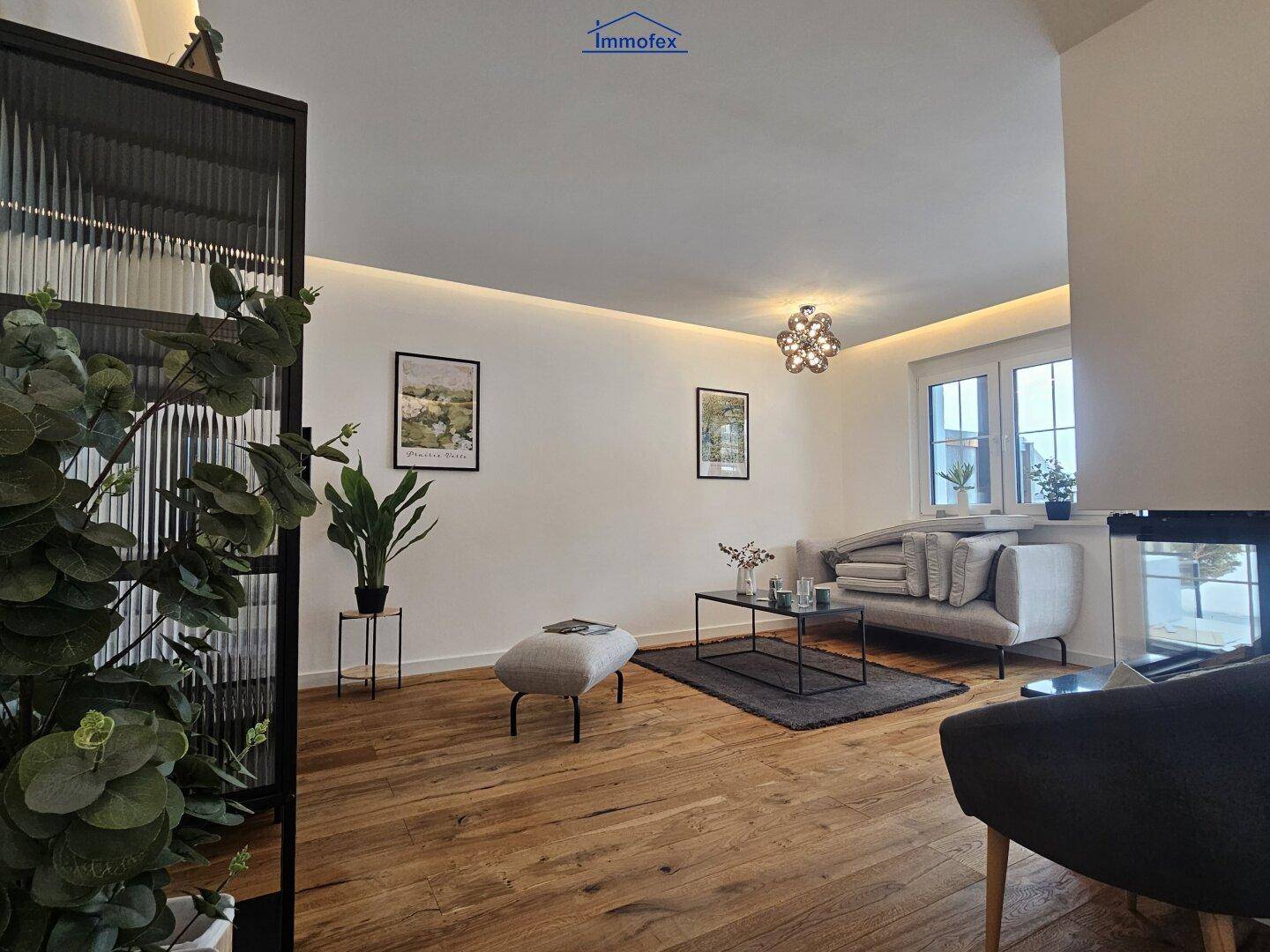 Helles Wohnzimmer mit Holzboden und großen Fenstern, bietet viel Tageslicht und eine moderne Einrichtung.