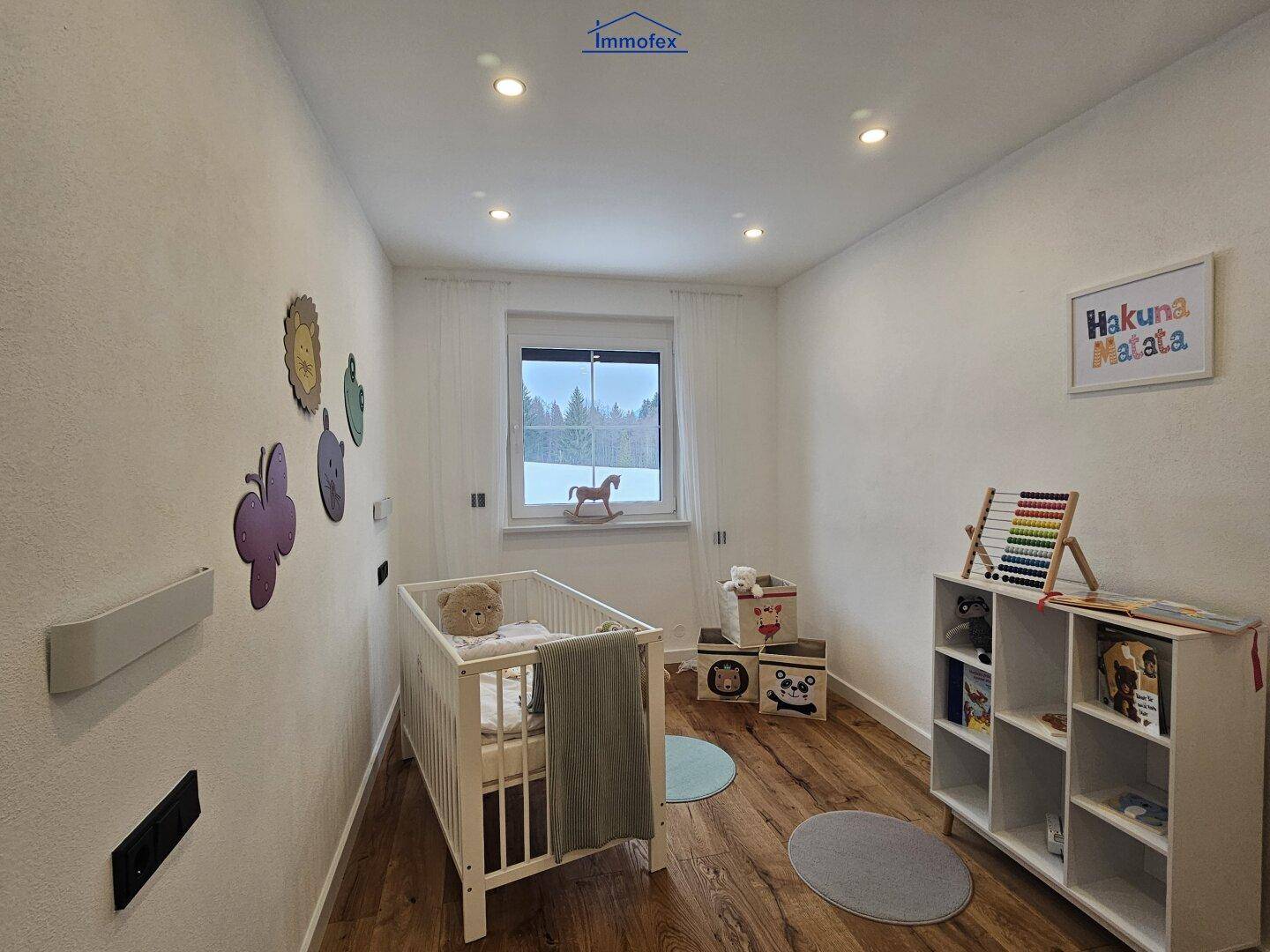 Freundliches Kinderzimmer mit Holzboden und Babybett, liebevoll dekoriert für die Kleinsten.