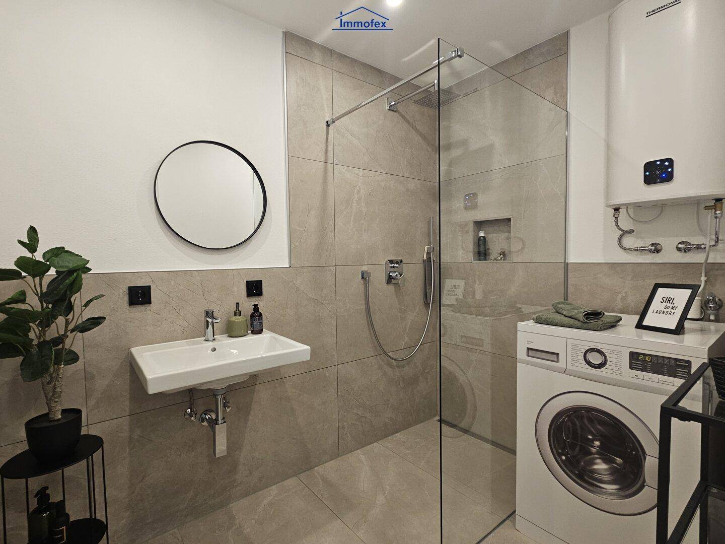 Modernes Badezimmer mit begehbarer Dusche, Waschmaschine und eleganten Fliesen.