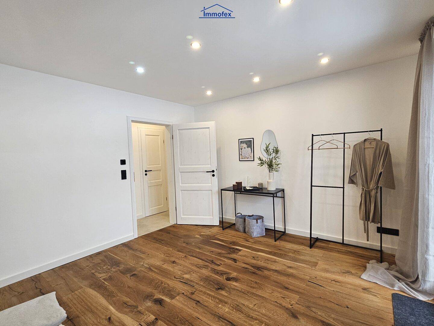 Geräumiges Schlafzimmer mit Holzboden und weißer Einrichtung, bietet viel Platz und Helligkeit.