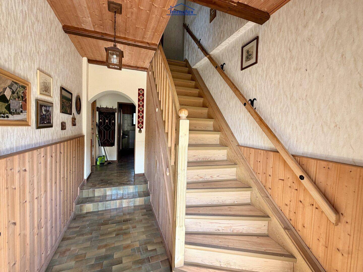 Geräumiger Flur mit Holzvertäfelung, Holzbalkendecke und Treppe zum Obergeschoss.