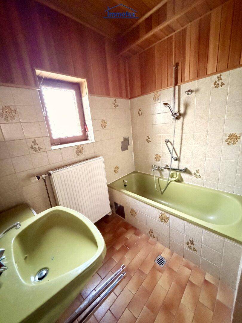 Badezimmer im Stil der 80er Jahre mit grüner Badewanne, Terrakotta-Fliesen und Holzdecke.