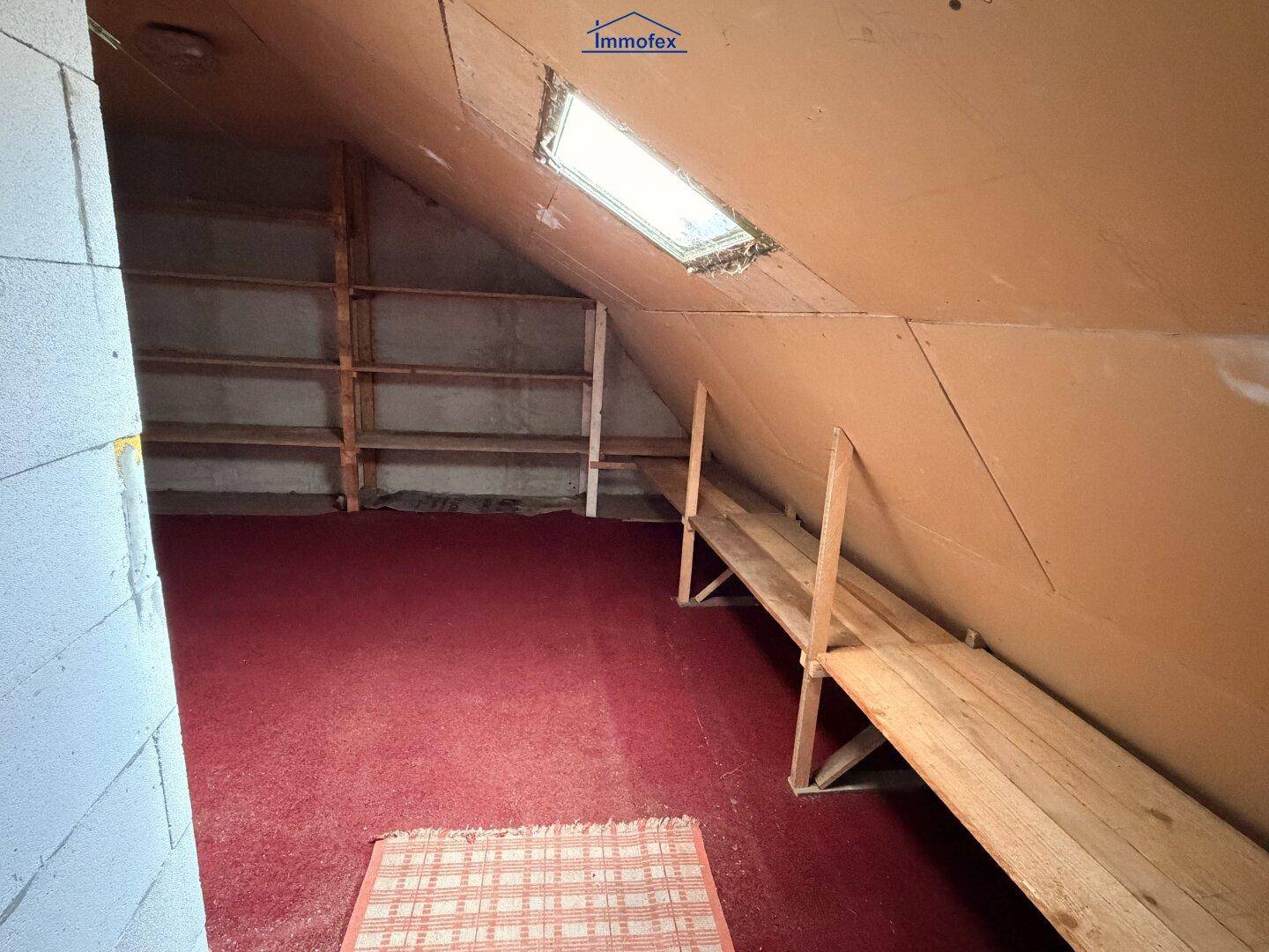 Dachboden als Lagerraum mit Holzregalen und einem Dachfenster für natürliches Licht.