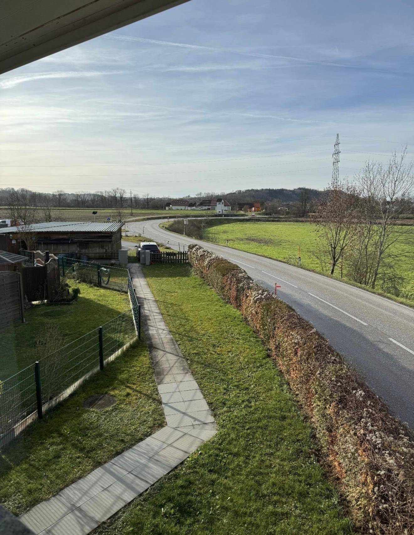Weitläufiger Blick über eine Landstraße, grüne Felder und die umliegende Landschaft von der Immobilie aus.