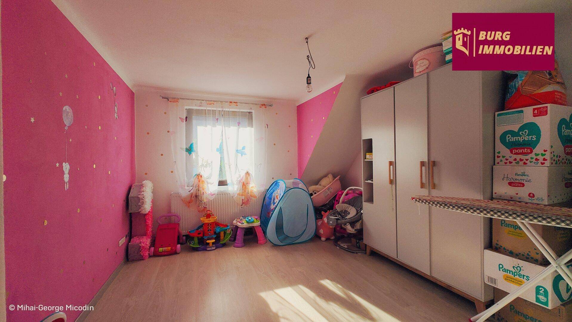 Helles Kinderzimmer mit farbenfrohen Wänden, Spielzeug und Dachschräge.