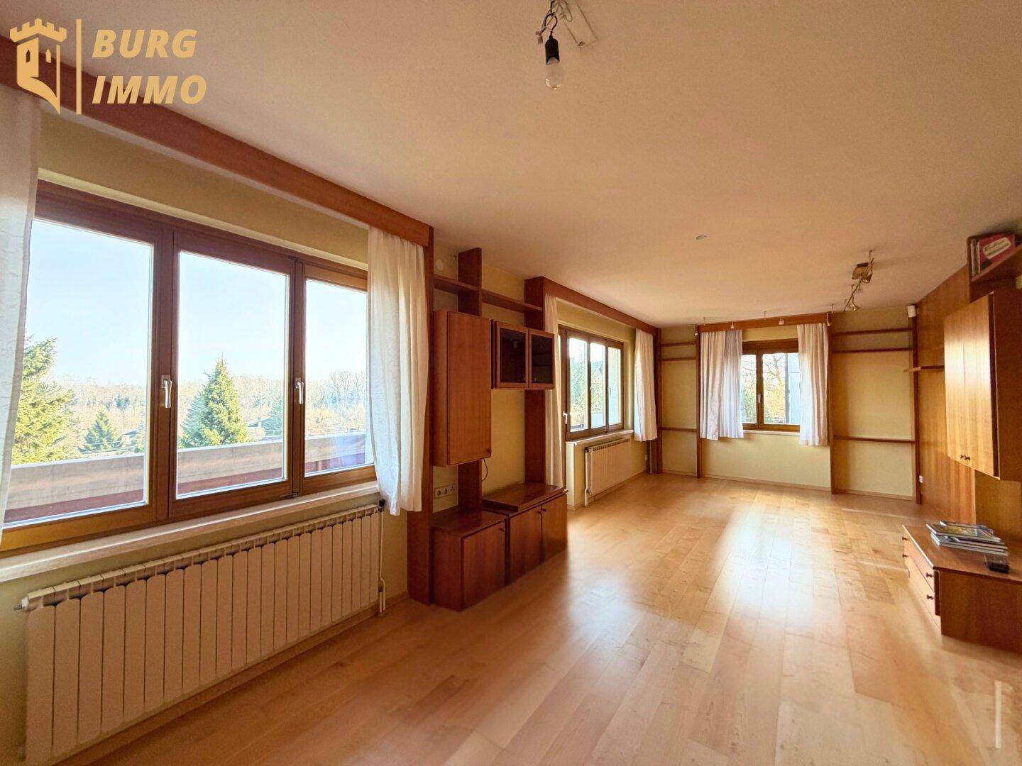 Geräumiger Wohn- und Essbereich mit Holzboden und großen Fenstern, bereit zur individuellen Gestaltung.