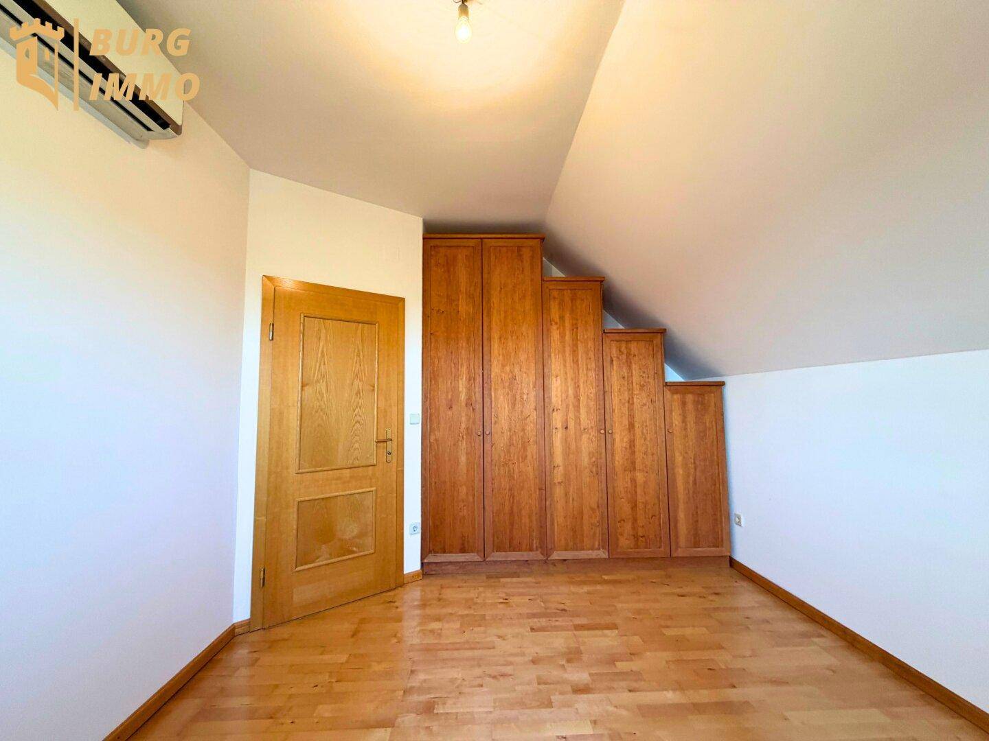 Schlafzimmer im Dachgeschoss mit Holzboden, Einbauschränken und Dachschräge.