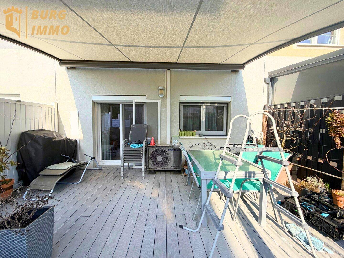 Überdachte Terrasse mit Holzboden und Gartenmöbeln, ideal für entspannte Stunden im Freien.