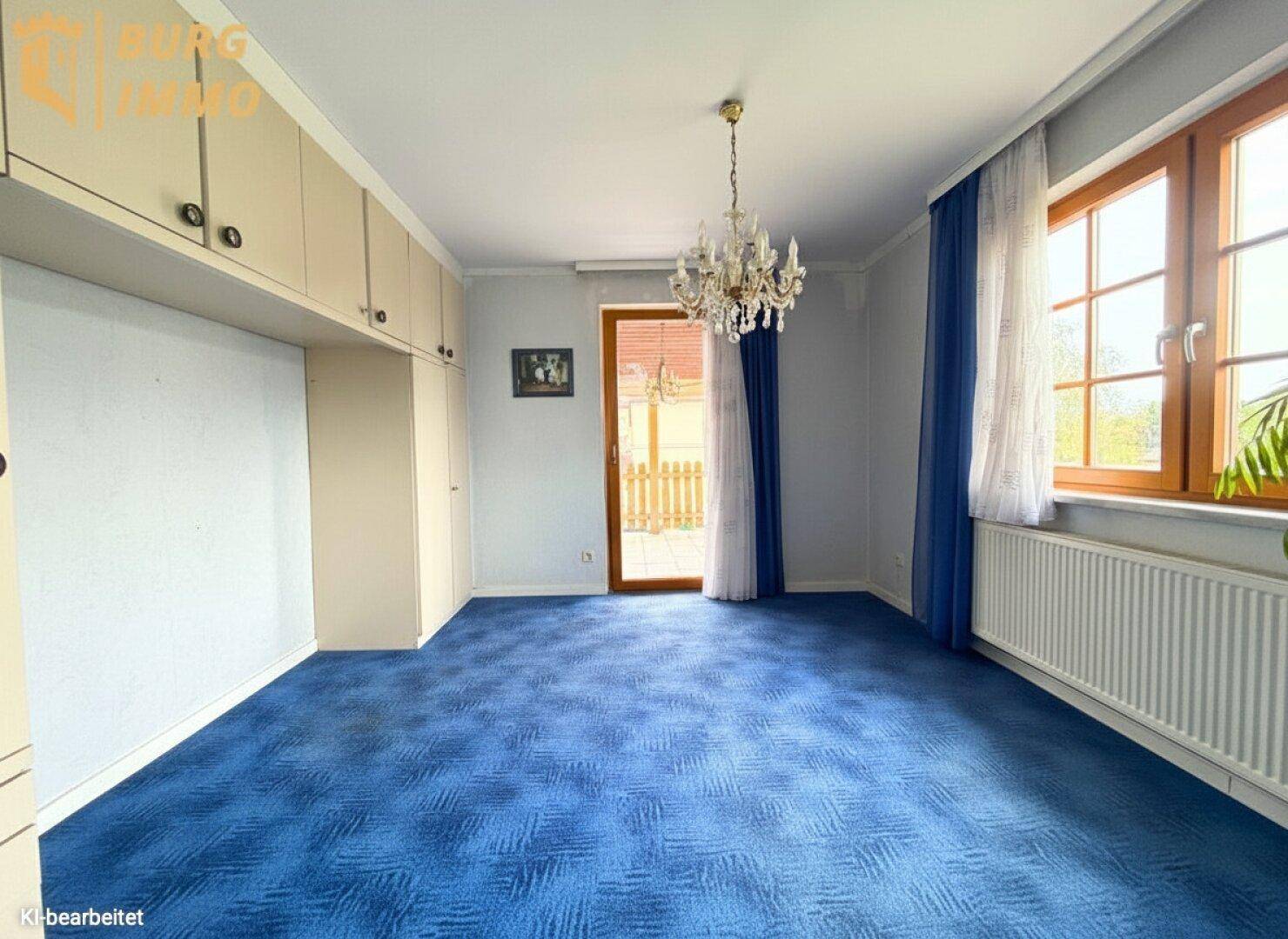 Schlafzimmer mit blauem Teppichboden, Einbauschränken und Zugang zum Balkon.