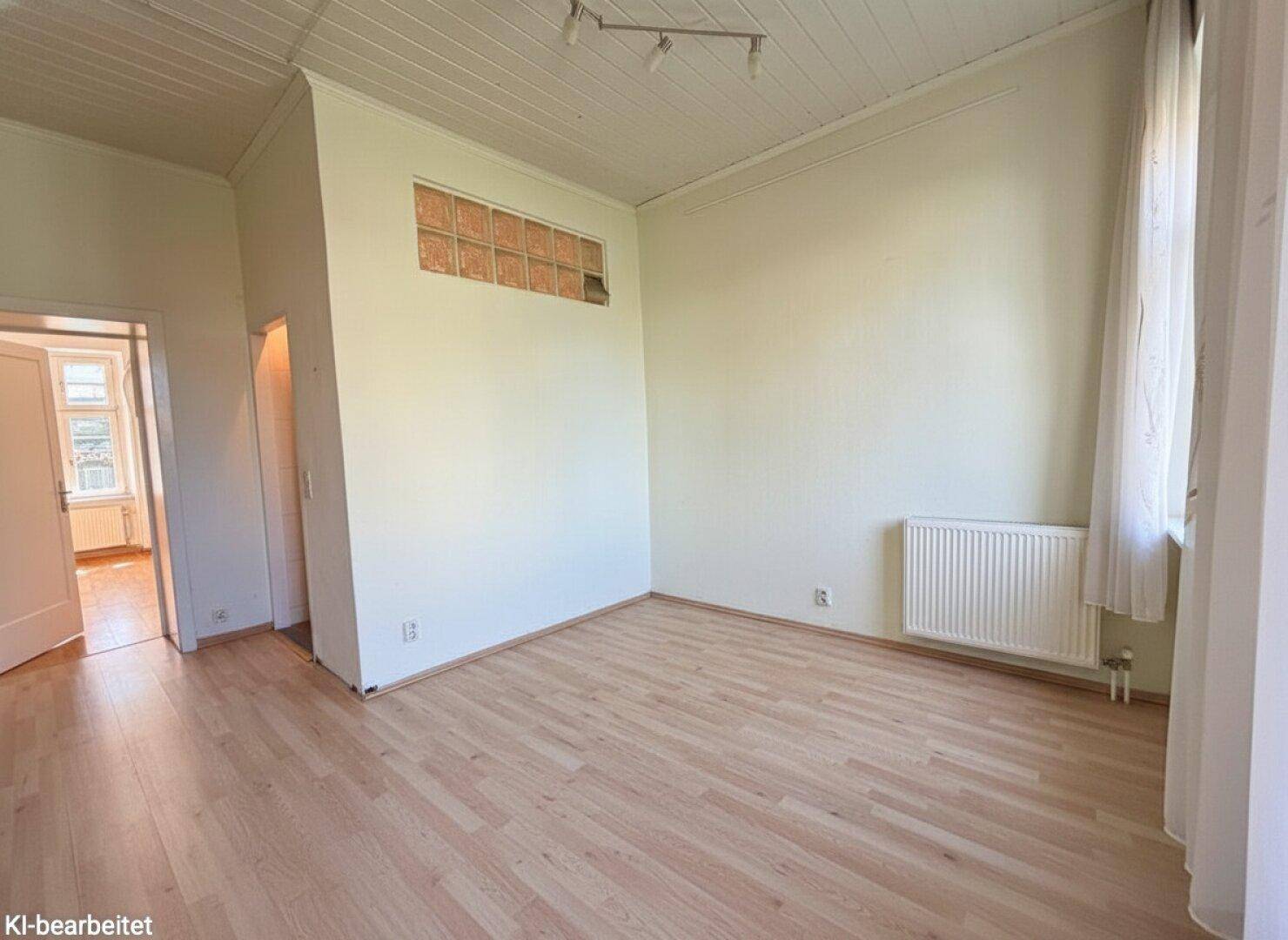 Helles Zimmer mit Parkettboden, Fenster und dekorativen Glasbausteinen.