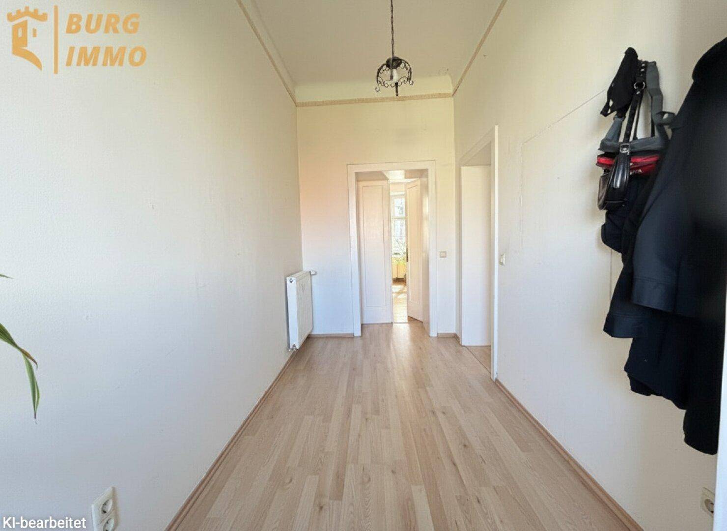 Langer Flur mit hellem Parkettboden, weißen Wänden und Zugang zu weiteren Räumen.