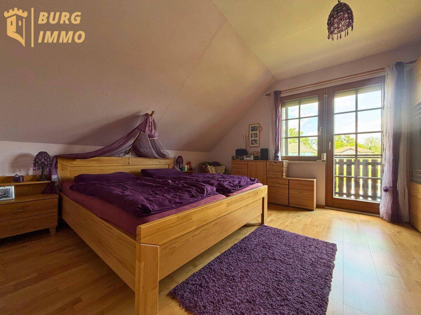 Geräumiges Schlafzimmer im Dachgeschoss mit Doppelbett, Holzboden und Zugang zum Balkon.