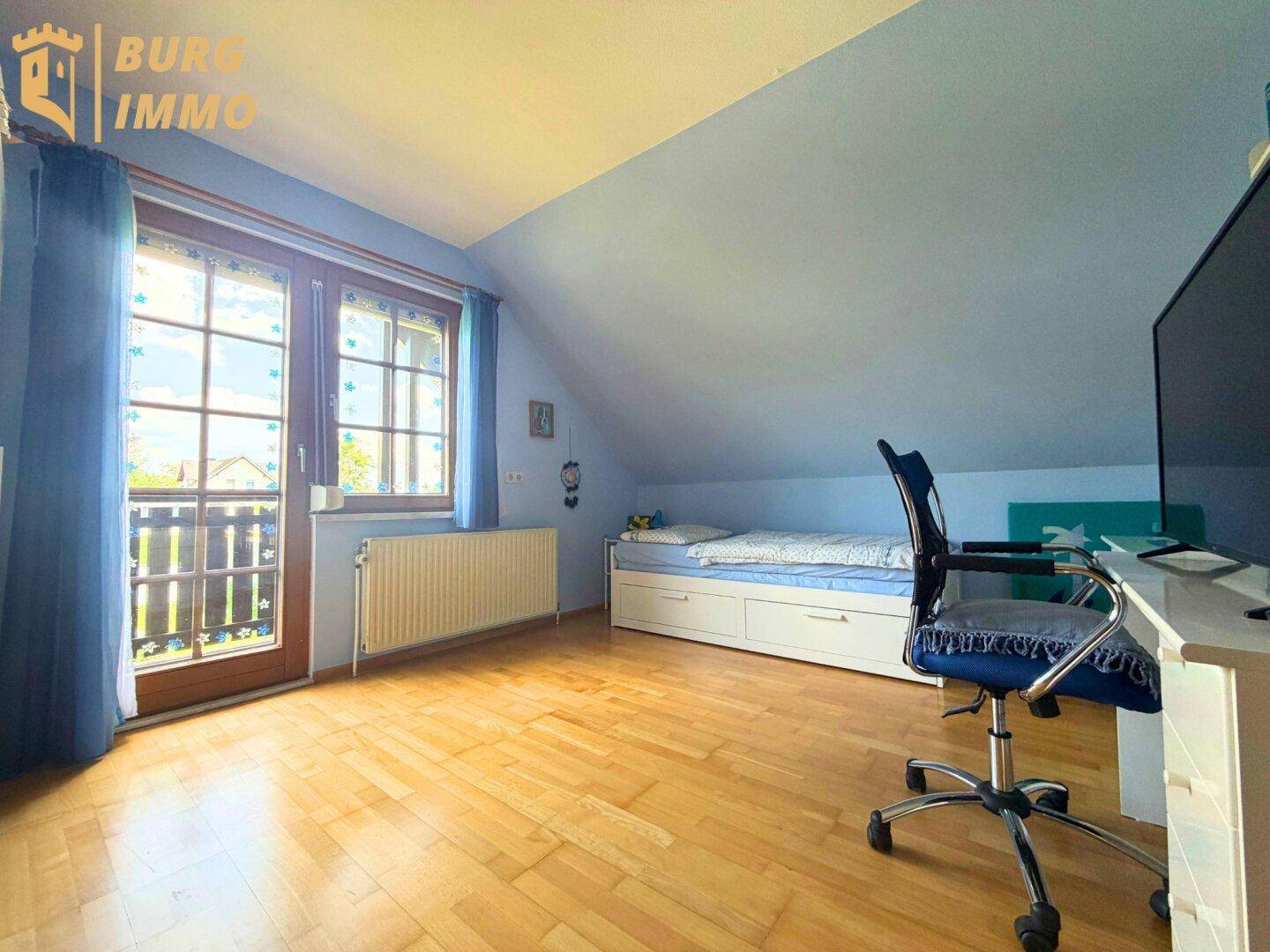 Helles Schlafzimmer mit Holzboden, blau gestrichenen Wänden und Balkonzugang.