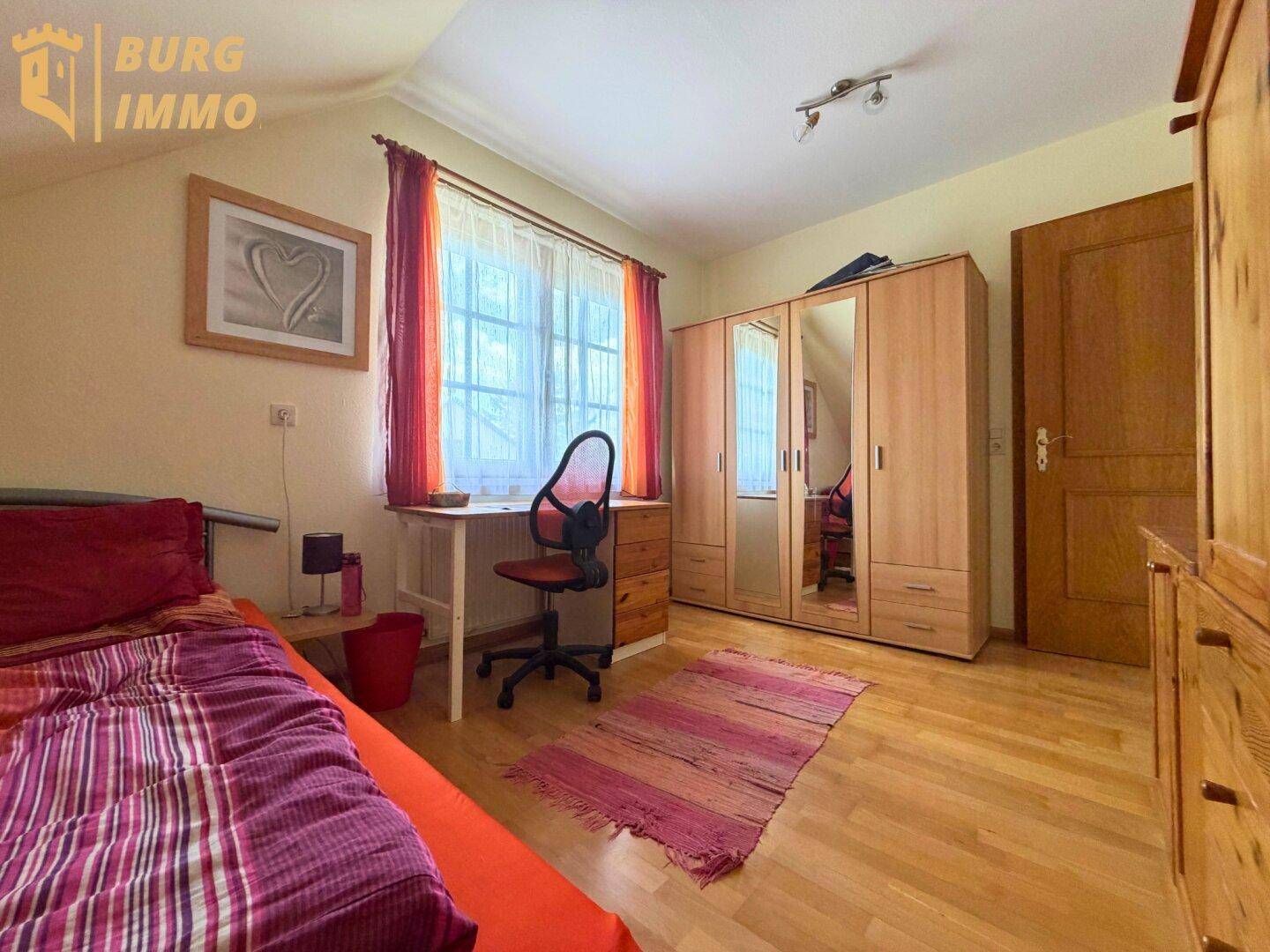 Schlafzimmer mit Holzboden, Kleiderschrank mit Spiegeltüren und einem Einzelbett.
