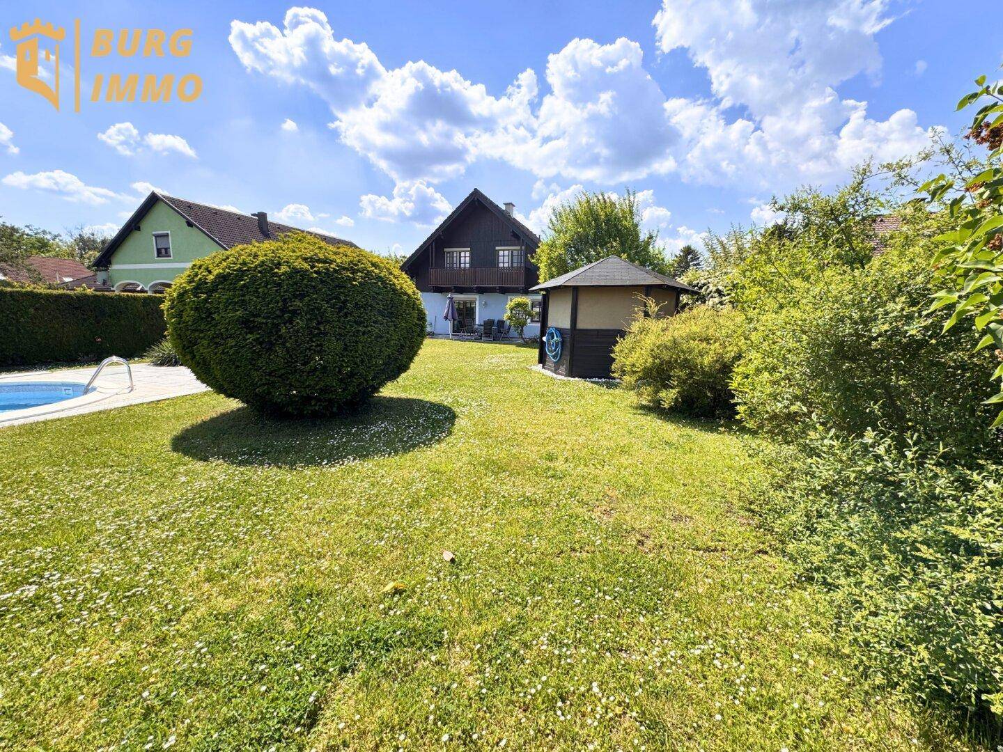 Weitläufiger Garten mit Pool, Gartenlaube und Blick auf das Wohnhaus.