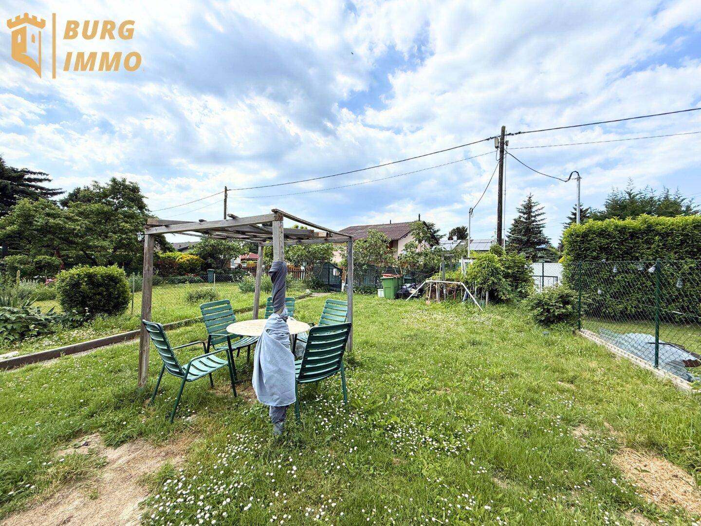 Gemütlicher Gartenbereich mit Sitzgelegenheiten unter einer Holzpergola und viel Grün.