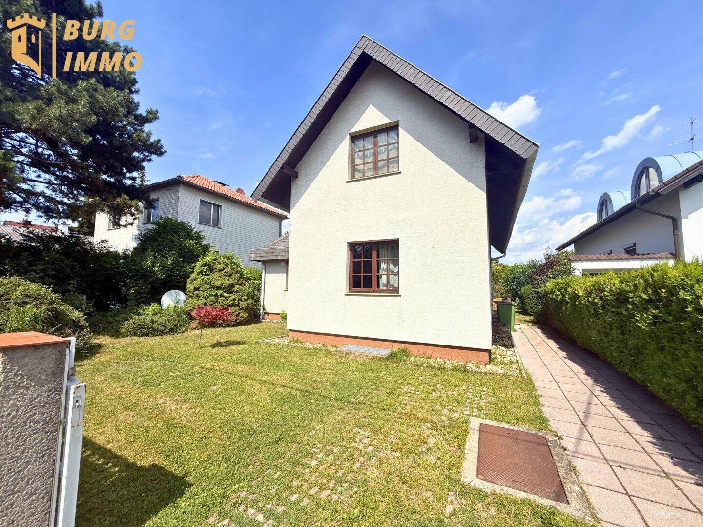 Seitenansicht des Hauses mit gepflegtem Garten, Rasenfläche und Gehweg.