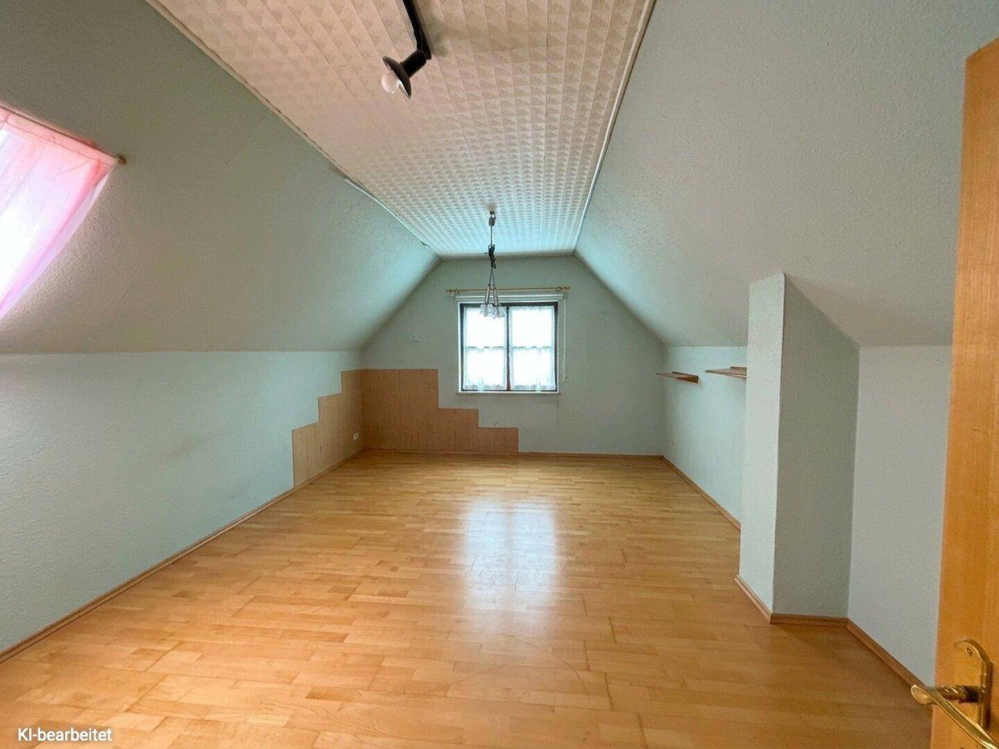 Dachgeschosszimmer mit Holzparkettboden, Dachschrägen und Fenster für natürliches Licht.