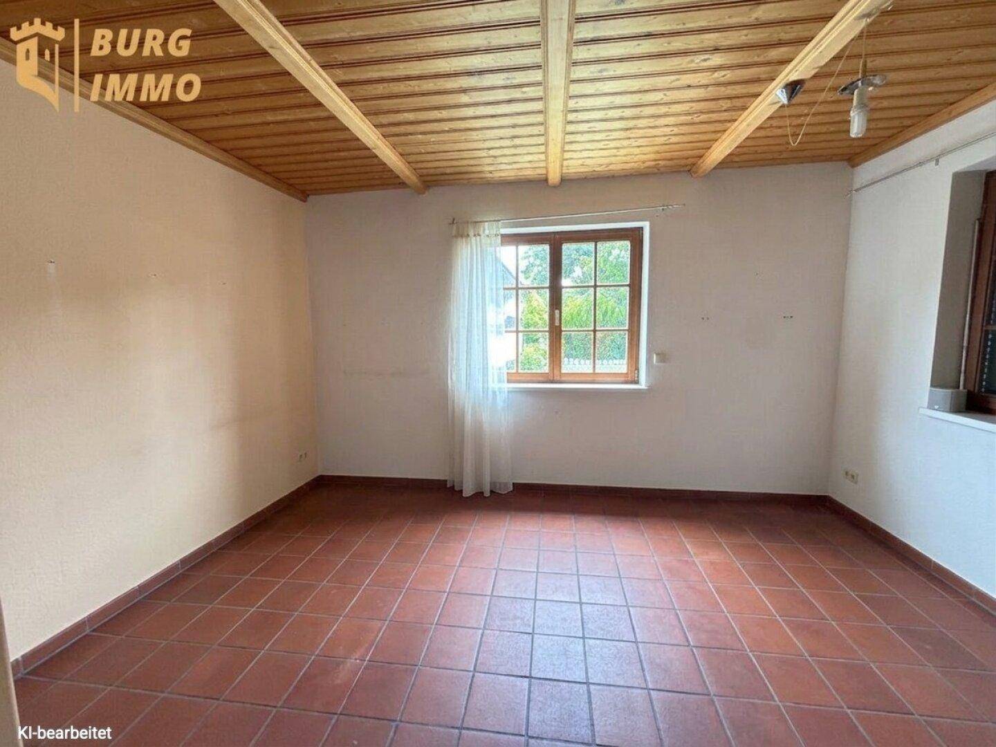 Geräumiges Zimmer mit Terrakottafliesen, Holzdecke und Blick in den Garten.