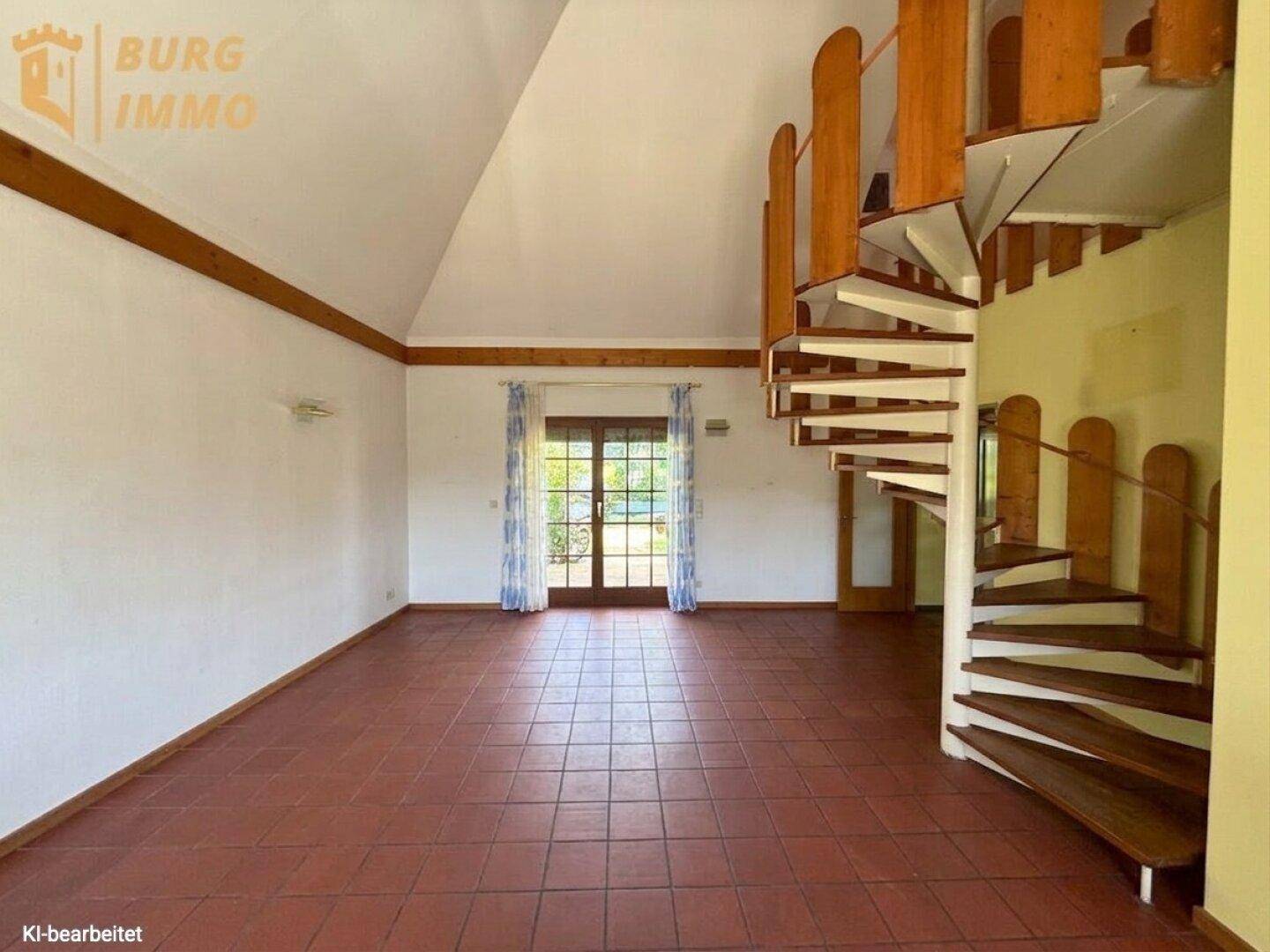 Geräumiger Wohnbereich mit Terrakottafliesen, hoher Decke und Wendeltreppe zum Obergeschoss.