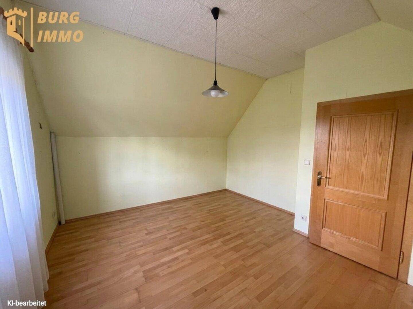 Helles Schlafzimmer mit Dachschrägen, Holzparkettboden und einem Fenster.