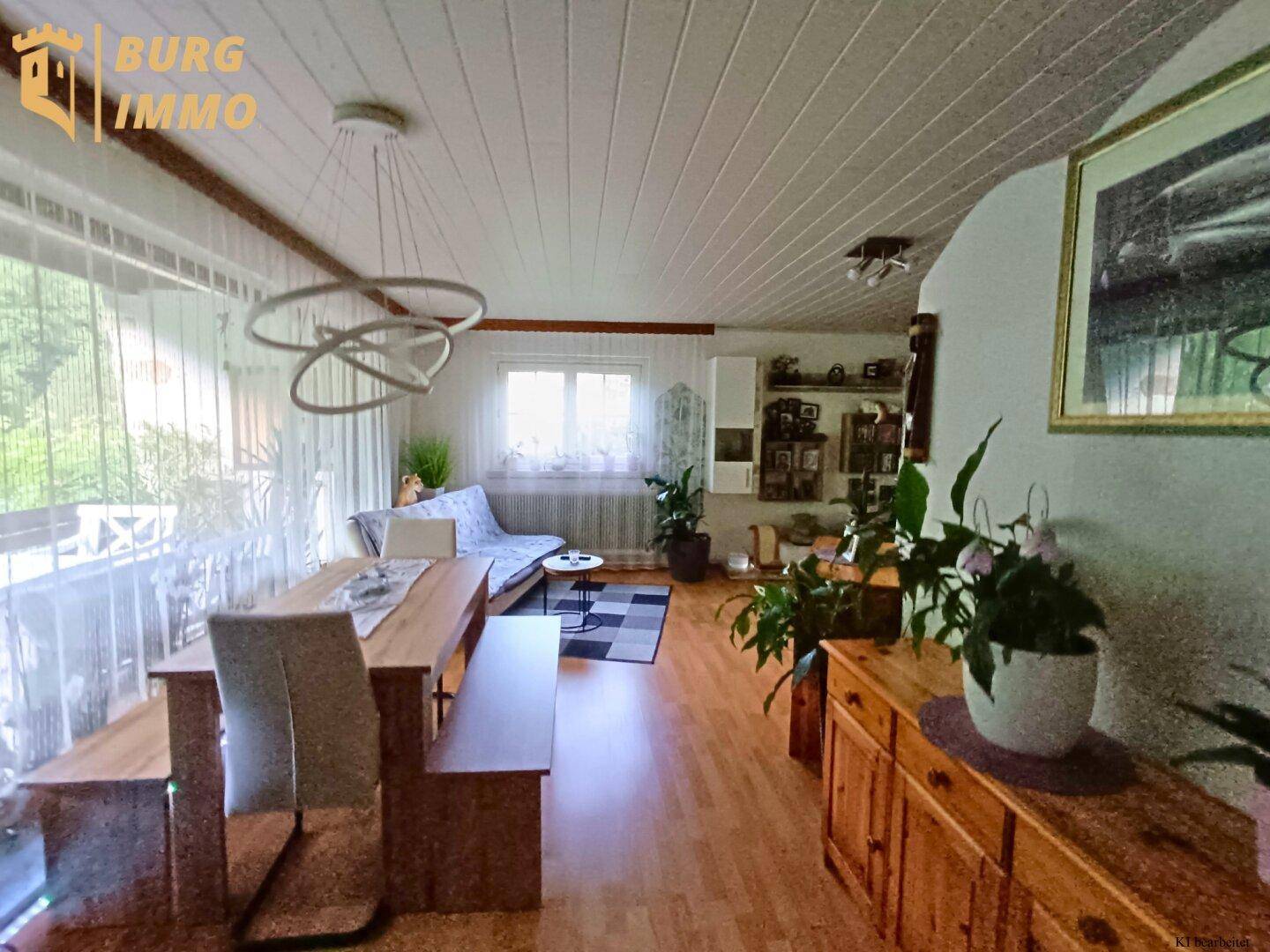 Geräumiger Wohn-Essbereich mit Holzboden, modernen Leuchten und Zugang zum Balkon.