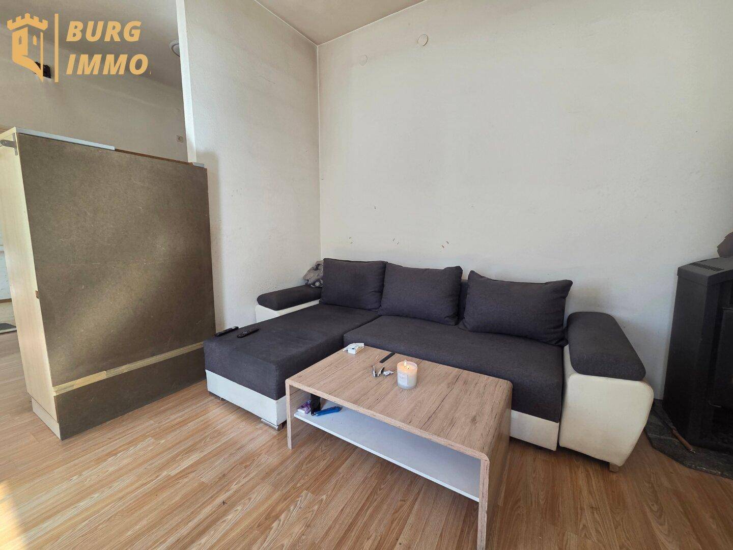 Wohnzimmer mit Ecksofa, Couchtisch und Laminatboden, einfach und funktional eingerichtet.