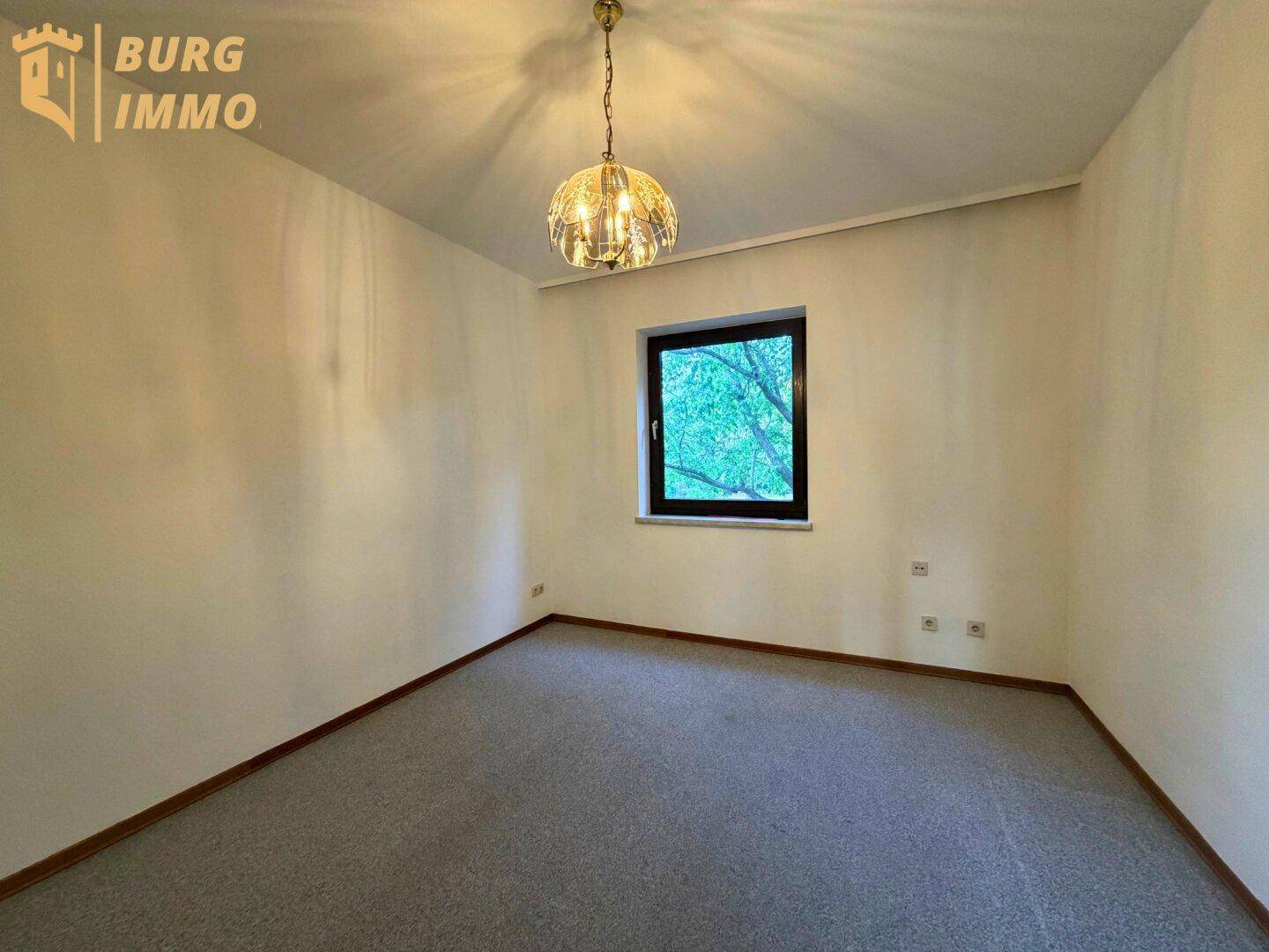 Schlafzimmer mit Teppichboden, hellem Anstrich und Fenster.