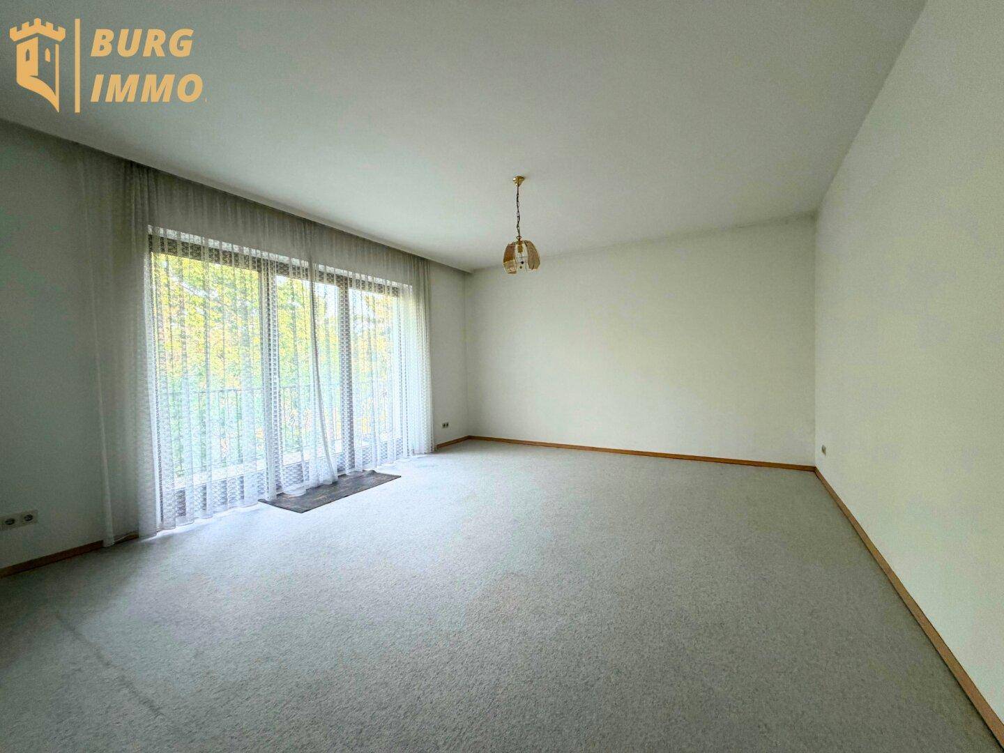 Heller Raum mit Teppichboden und Zugang zu einem französischen Balkon.