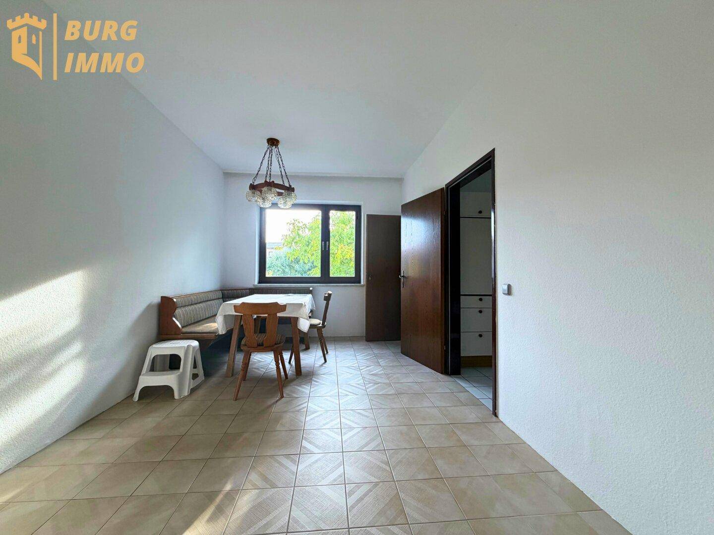 Essbereich mit gefliestem Boden, Fenster und traditionellen Holzmöbeln.