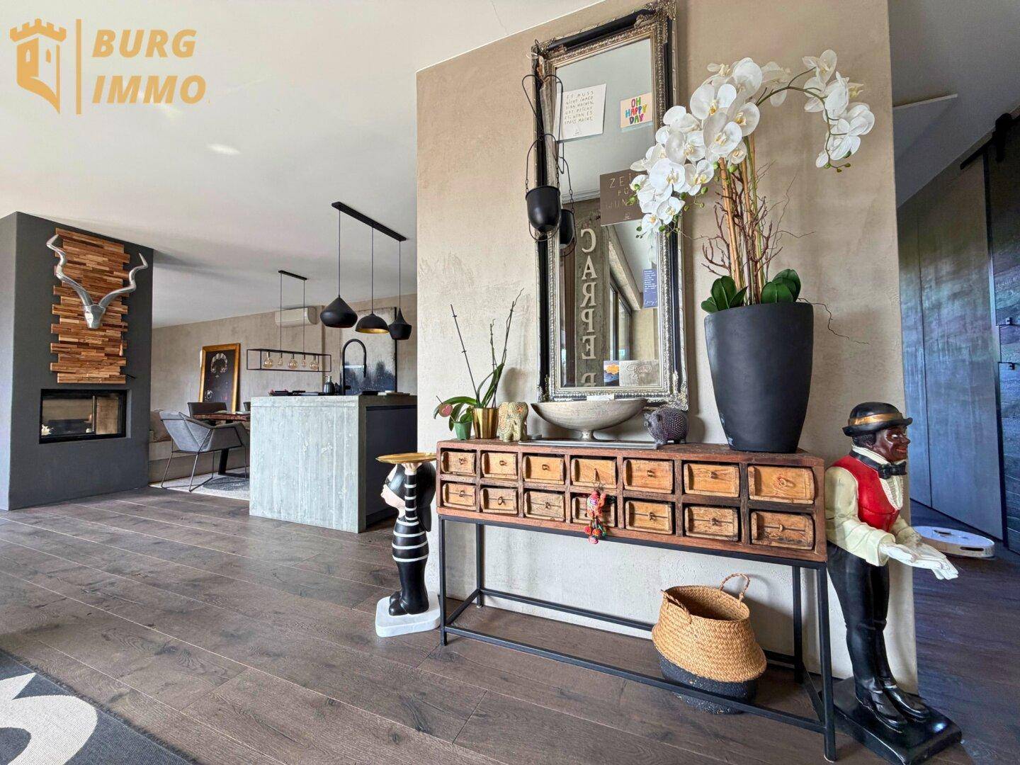 Stilvoller Eingangsbereich mit Holzboden, dekorativer Konsole und Blick in den offenen Wohnbereich.